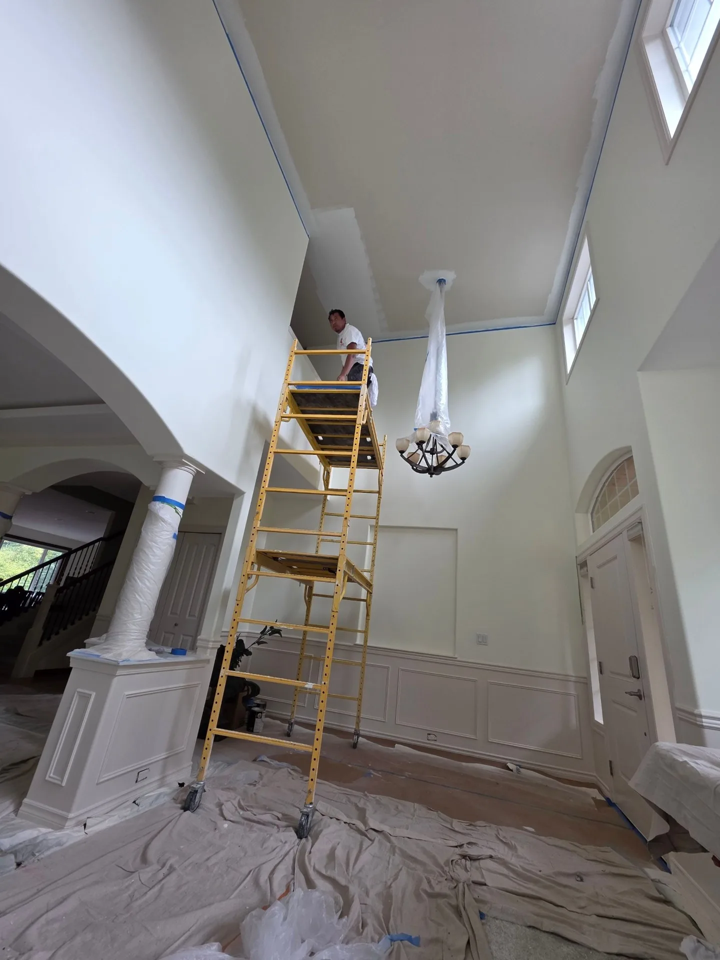 Painter on scaffolding painting high ceilings in foyer